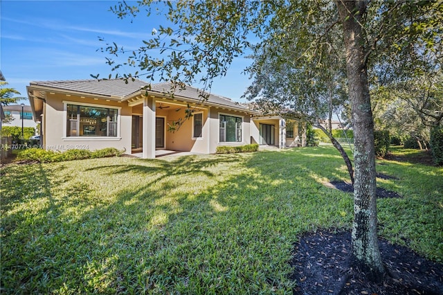 rear view of property with a lawn, ceiling fan, and a patio area