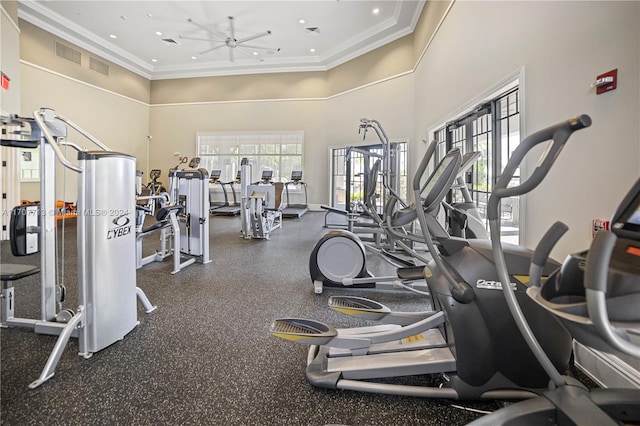 workout area featuring ceiling fan, a towering ceiling, and crown molding