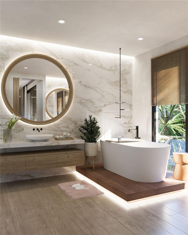 bathroom with a washtub, vanity, tile walls, hardwood / wood-style floors, and plenty of natural light