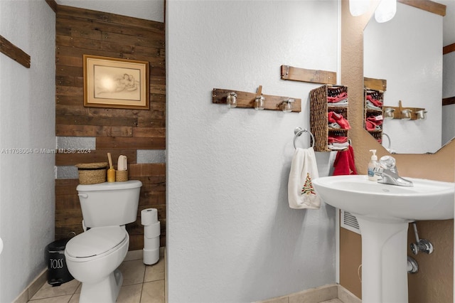 bathroom featuring toilet, tile patterned floors, and wooden walls