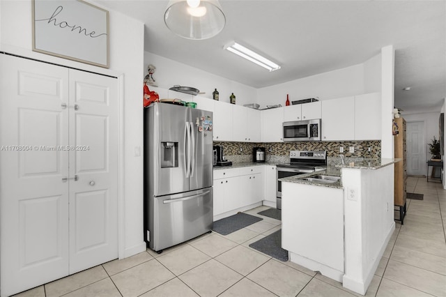 kitchen with light tile patterned flooring, white cabinetry, backsplash, and appliances with stainless steel finishes