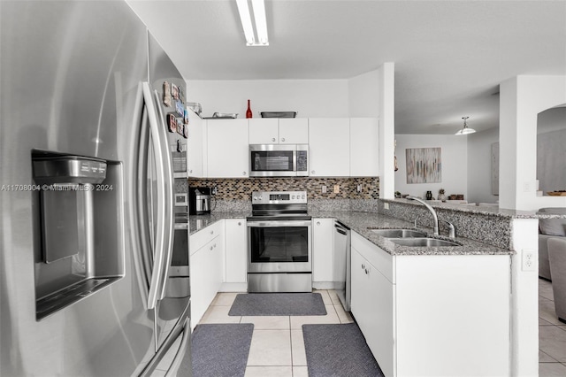 kitchen with kitchen peninsula, stainless steel appliances, sink, light tile patterned floors, and white cabinetry