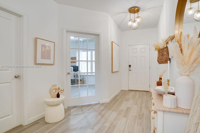 doorway with an inviting chandelier and light wood-type flooring