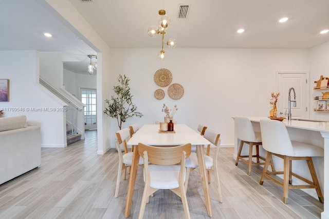 dining area featuring sink, a notable chandelier, and light wood-type flooring