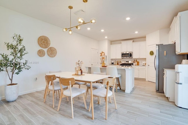 dining room featuring a notable chandelier and light wood-type flooring