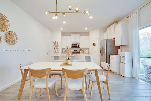 kitchen featuring appliances with stainless steel finishes, a kitchen island with sink, pendant lighting, a chandelier, and white cabinetry