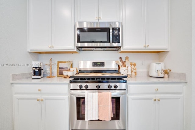 kitchen with white cabinetry, light stone counters, and appliances with stainless steel finishes