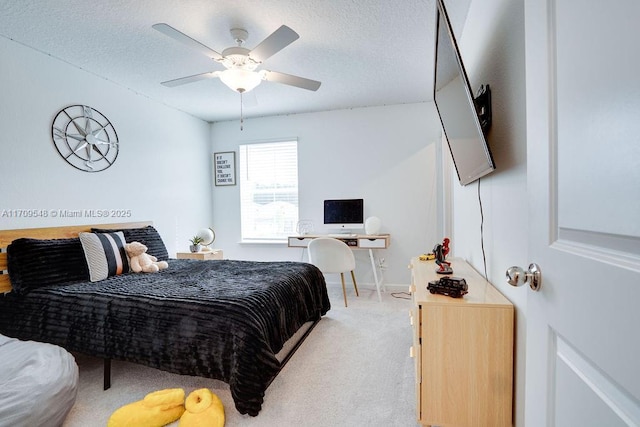 carpeted bedroom featuring ceiling fan and a textured ceiling