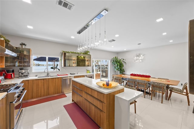 kitchen featuring pendant lighting, a kitchen island, sink, stainless steel appliances, and light tile patterned floors