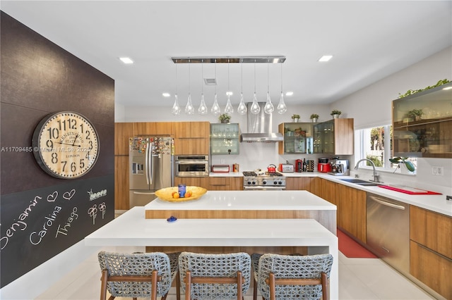 kitchen featuring appliances with stainless steel finishes, a kitchen island, a kitchen bar, decorative light fixtures, and sink