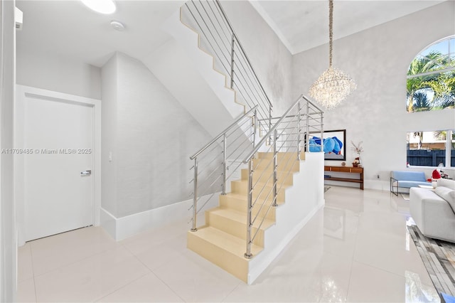 staircase with a high ceiling, tile patterned floors, and a chandelier