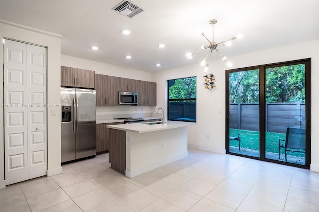 kitchen with dark brown cabinetry, sink, stainless steel appliances, a kitchen island with sink, and light tile patterned floors