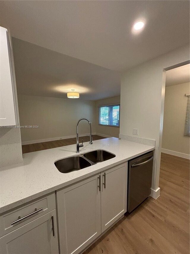 kitchen featuring light stone counters, stainless steel dishwasher, sink, light hardwood / wood-style flooring, and white cabinetry