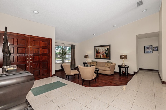 tiled living room featuring a textured ceiling and vaulted ceiling