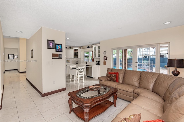 tiled living room featuring french doors and a textured ceiling