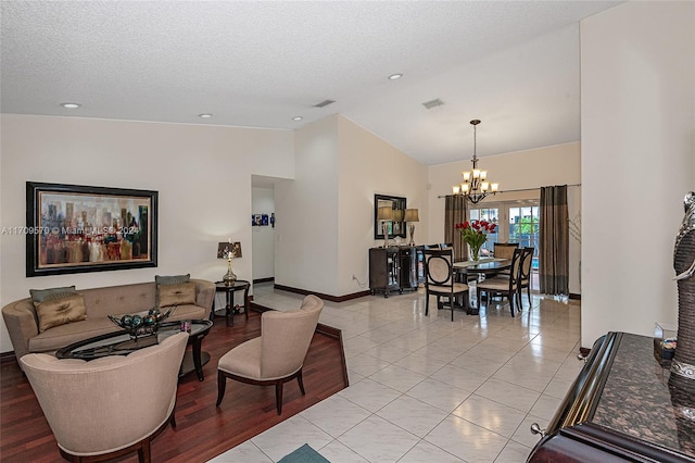 living room featuring a chandelier, a textured ceiling, high vaulted ceiling, and light hardwood / wood-style flooring