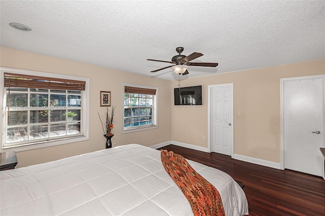 bedroom with a textured ceiling, ceiling fan, and dark wood-type flooring