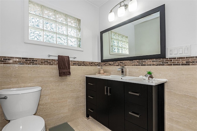 bathroom with tile patterned floors, vanity, toilet, and tile walls