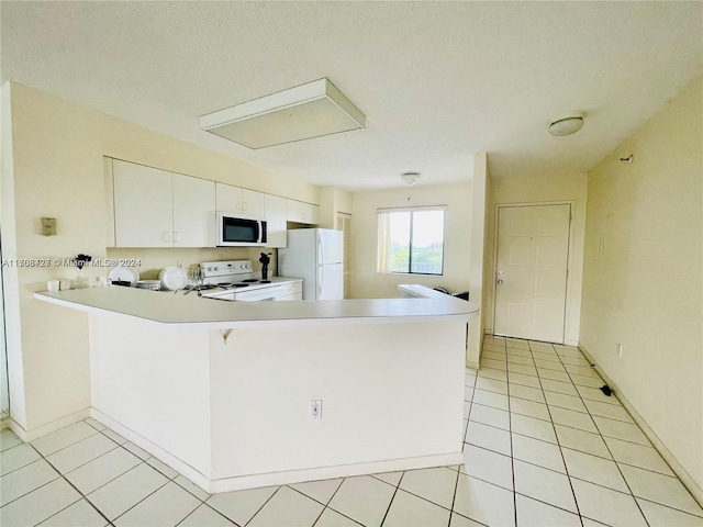 kitchen with white appliances, kitchen peninsula, light tile patterned floors, a textured ceiling, and white cabinetry