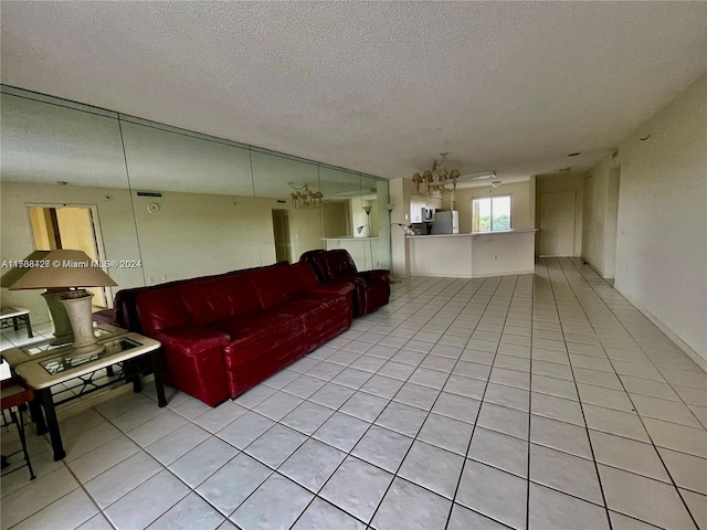 living room featuring light tile patterned floors, a textured ceiling, and a notable chandelier