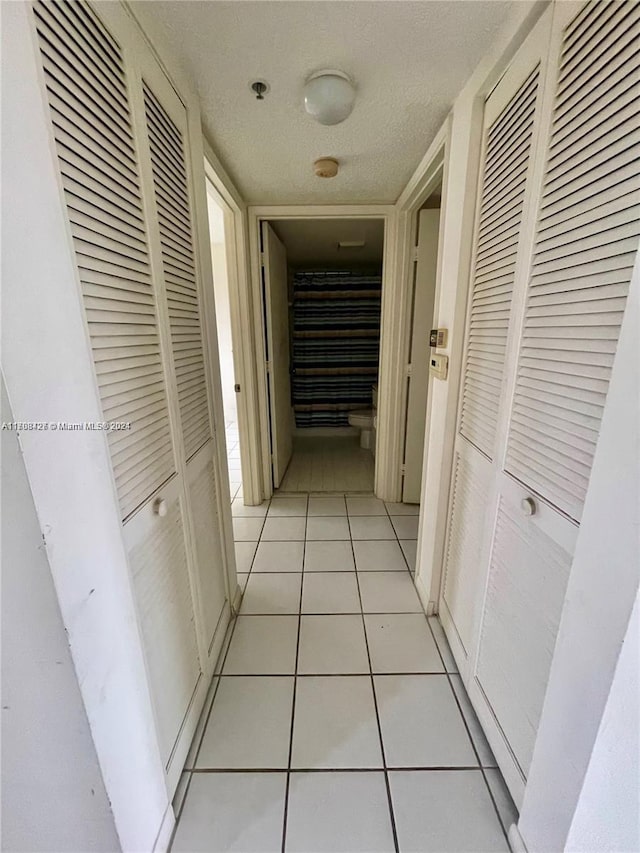 hallway featuring light tile patterned floors and a textured ceiling