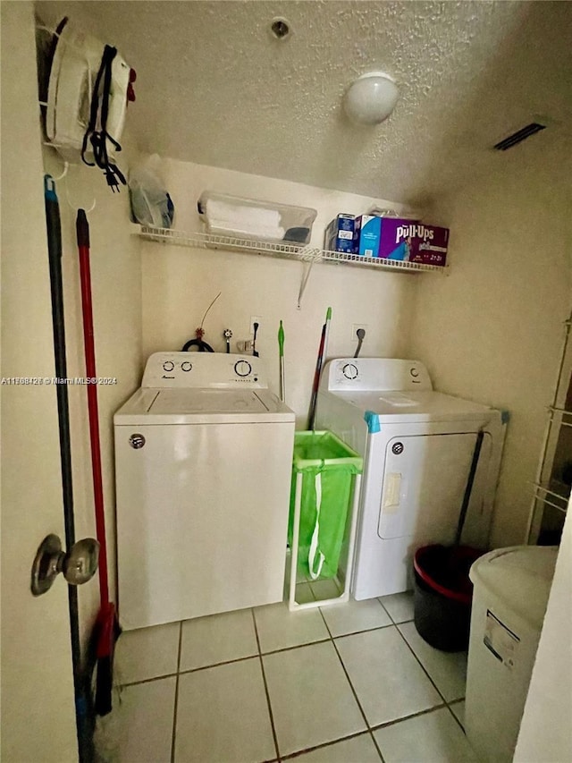 laundry room with light tile patterned floors, a textured ceiling, and separate washer and dryer