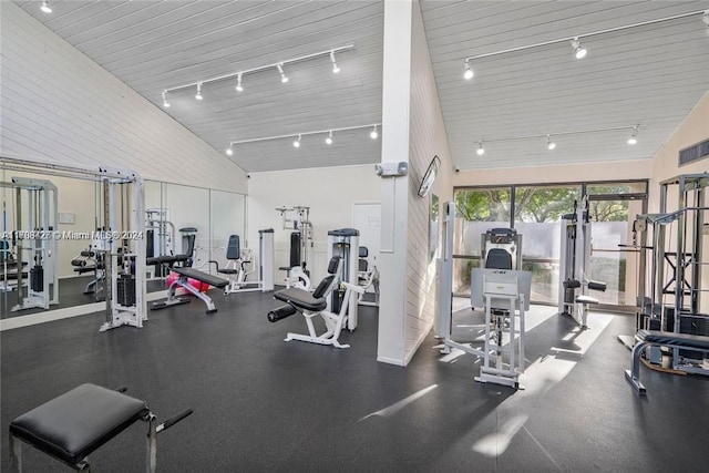 exercise room with track lighting and high vaulted ceiling