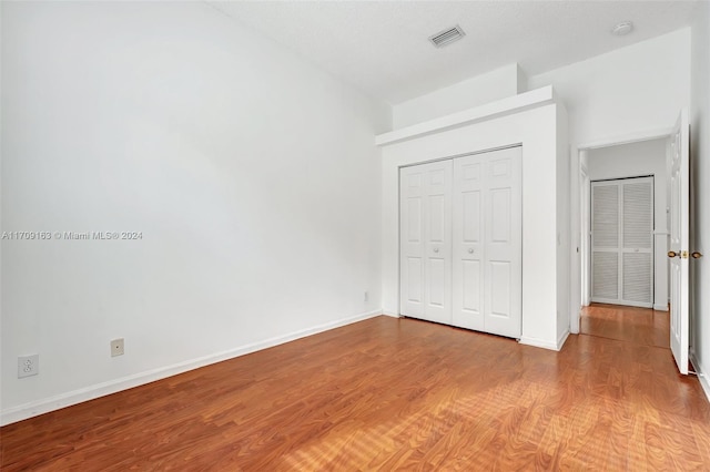 unfurnished bedroom featuring hardwood / wood-style flooring, a textured ceiling, and a closet