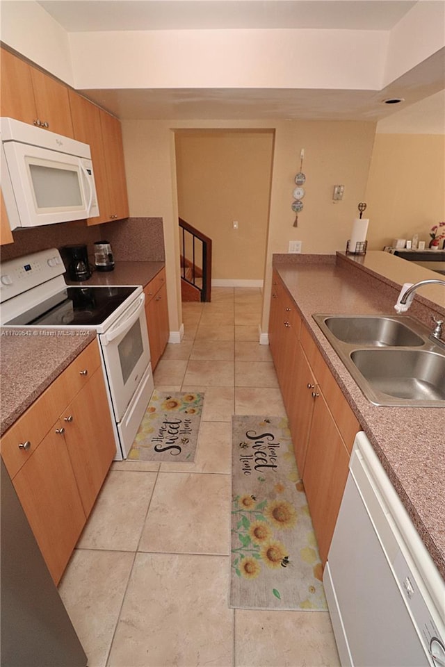 kitchen with white appliances, sink, and light tile patterned floors