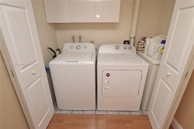 washroom featuring cabinets, light hardwood / wood-style floors, and independent washer and dryer