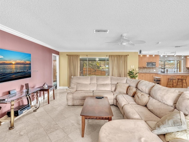 living room with track lighting, a textured ceiling, ceiling fan, crown molding, and sink