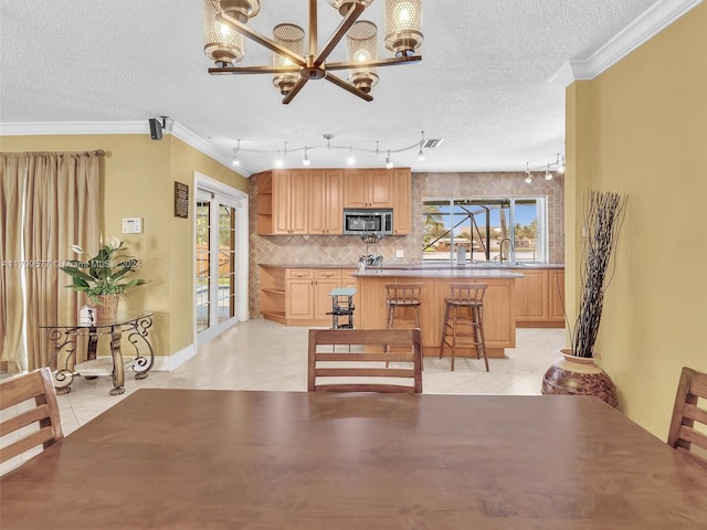 kitchen featuring light tile patterned floors, a textured ceiling, crown molding, and a healthy amount of sunlight