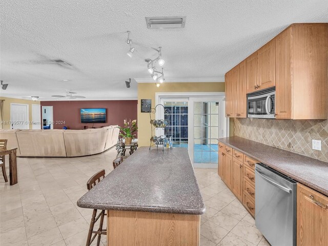 8910 NW 7th Ct, Pembroke Pines, FL 33024 - kitchen featuring stainless steel appliances, a kitchen breakfast bar, tasteful backsplash, a textured ceiling, and open floor plan