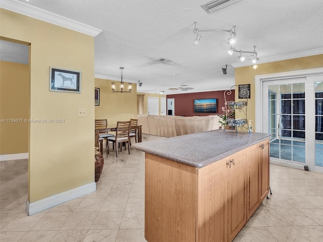 kitchen featuring an inviting chandelier, hanging light fixtures, a textured ceiling, and ornamental molding