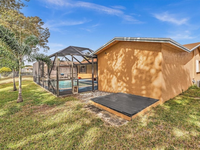 back of house featuring a lanai, a yard, and a pool