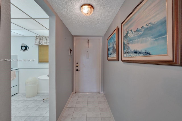 corridor featuring light tile patterned floors and a textured ceiling