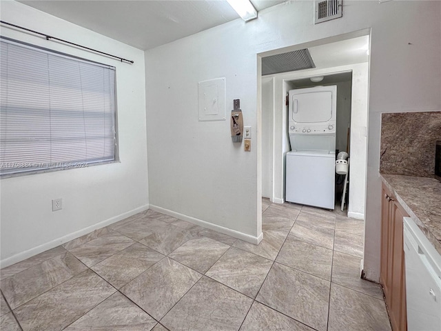 interior space featuring electric panel, stacked washer and dryer, and light tile patterned flooring