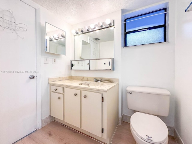 bathroom with vanity, wood-type flooring, a textured ceiling, and toilet