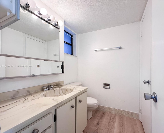 bathroom with hardwood / wood-style floors, vanity, a textured ceiling, and toilet