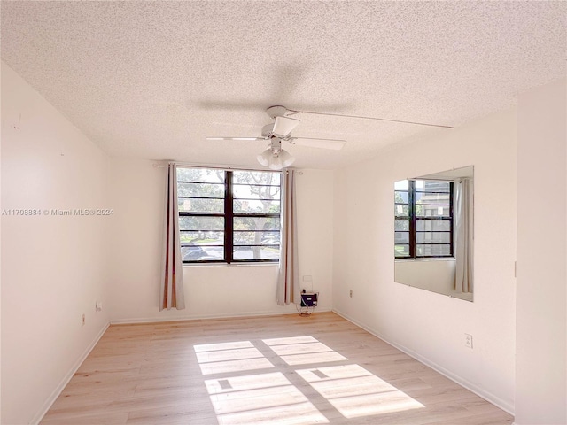 spare room featuring ceiling fan, a healthy amount of sunlight, a textured ceiling, and light hardwood / wood-style flooring