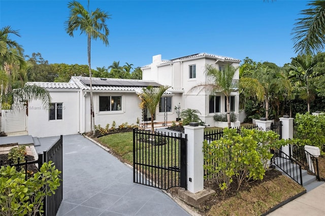 mediterranean / spanish home with a front yard and solar panels