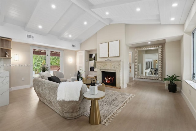 living room with a premium fireplace, beam ceiling, and light wood-type flooring