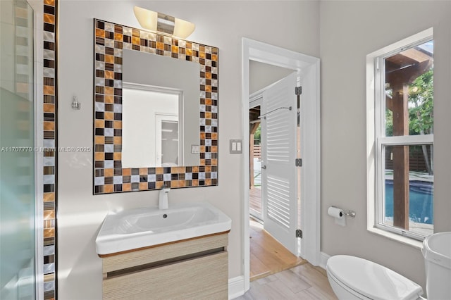 bathroom featuring vanity, backsplash, hardwood / wood-style flooring, and toilet