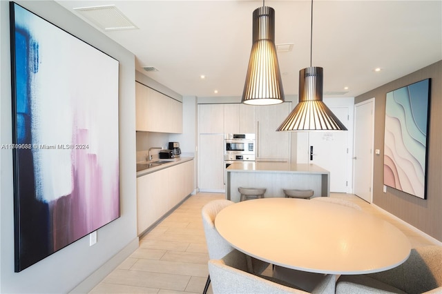 kitchen featuring sink, a center island, stainless steel double oven, pendant lighting, and light hardwood / wood-style floors