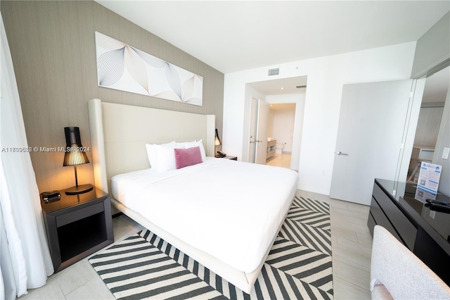 bedroom with light wood-type flooring and connected bathroom