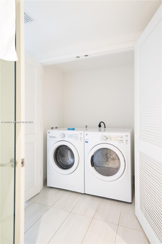 washroom featuring washer and clothes dryer and light tile patterned flooring