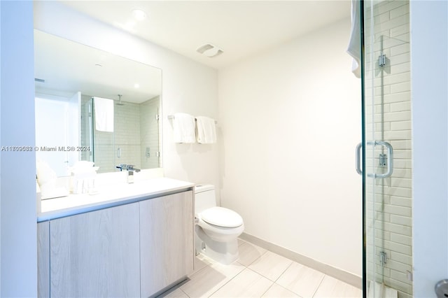 bathroom featuring tile patterned floors, vanity, toilet, and a shower with door