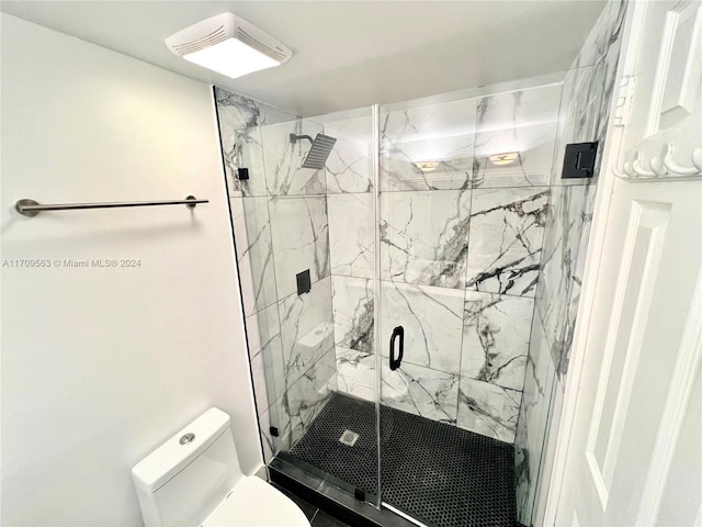 bathroom featuring toilet and a shower with shower door