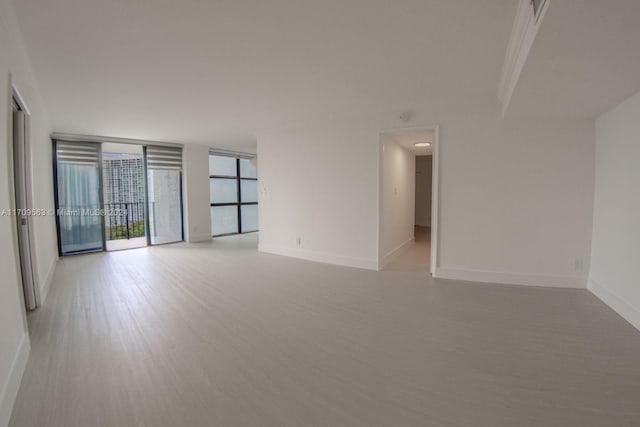 empty room with light hardwood / wood-style flooring and a wall of windows