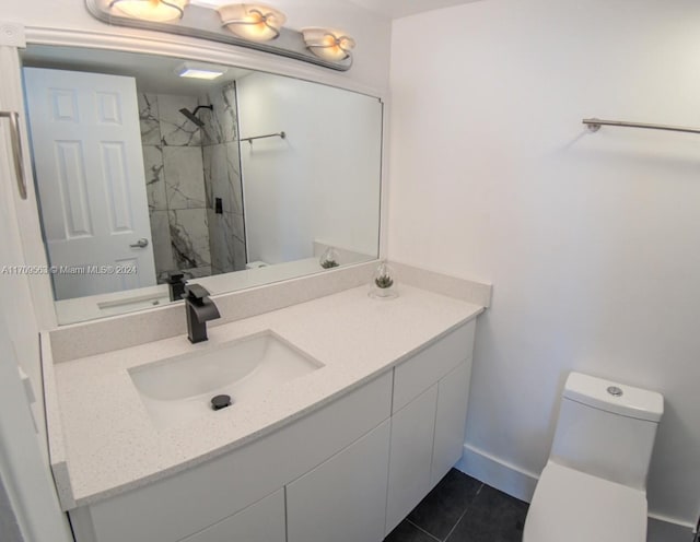 bathroom with tile patterned floors, vanity, toilet, and tiled shower